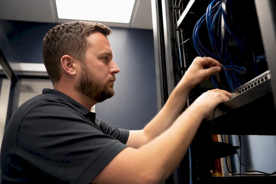 Hands connecting network cables in IT closet