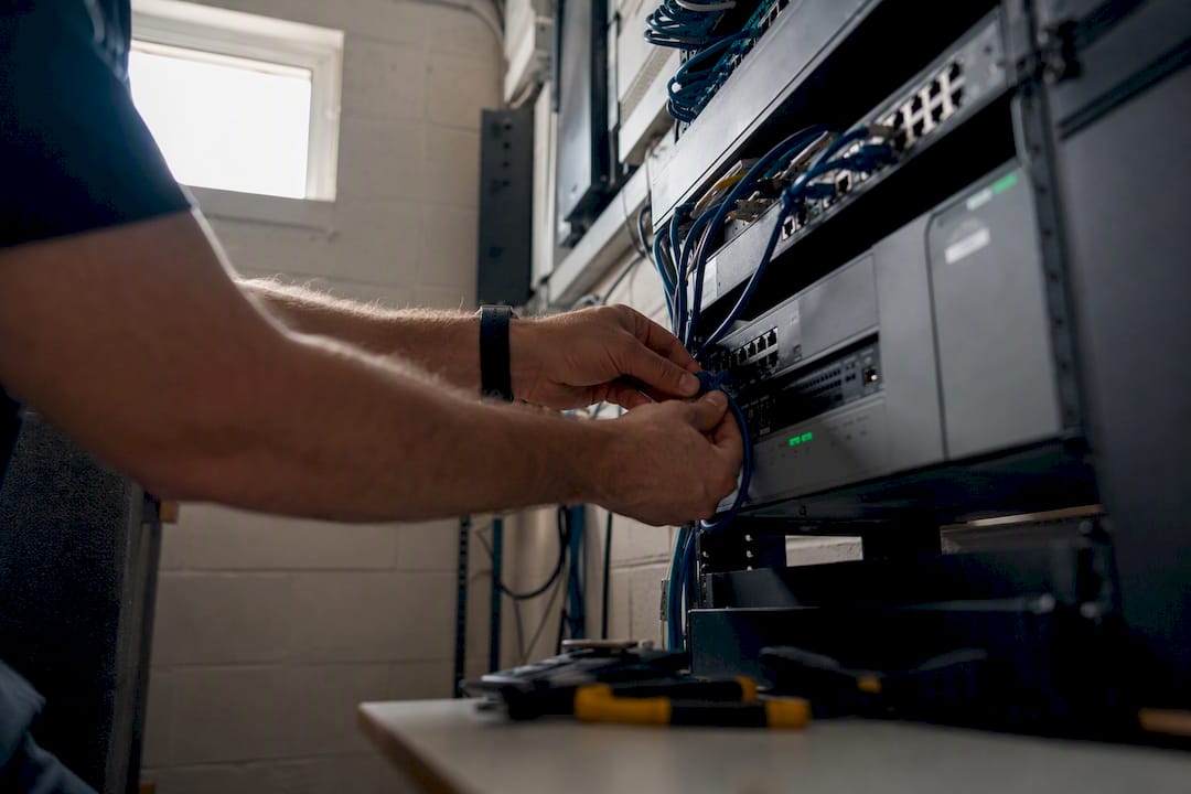 Hands testing network cable in server closet